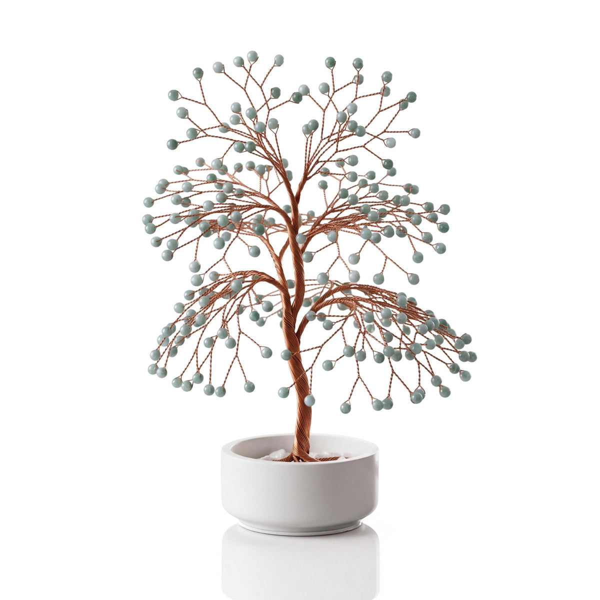 Copper wire tree with polished pale green Burmese jadeite beads in a plain white ceramic bowl