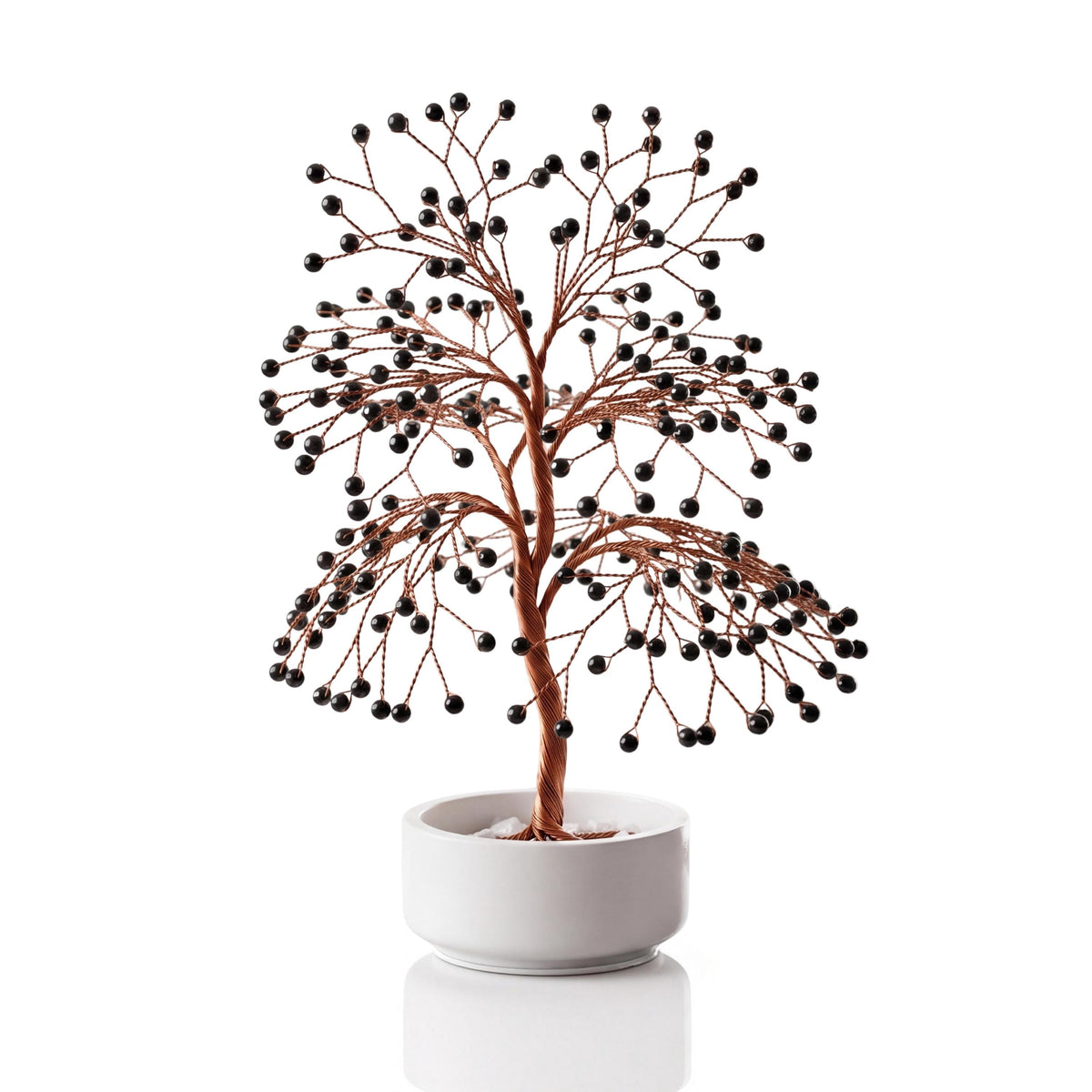 Copper wire tree with polished glossy jet black obsidian spheres in a plain white ceramic bowl