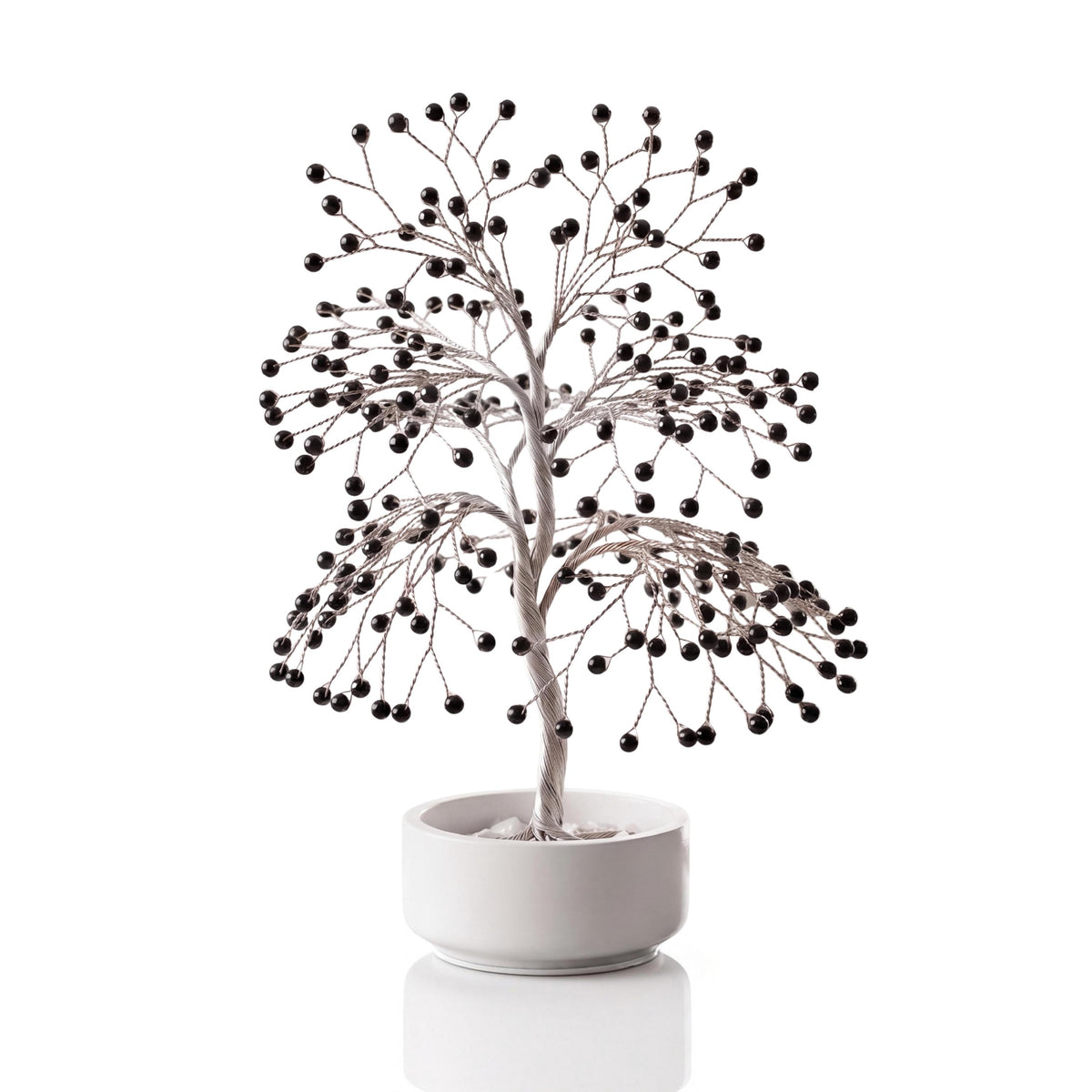 Silver-plated wire tree with polished glossy jet black obsidian spheres in a white ceramic bowl