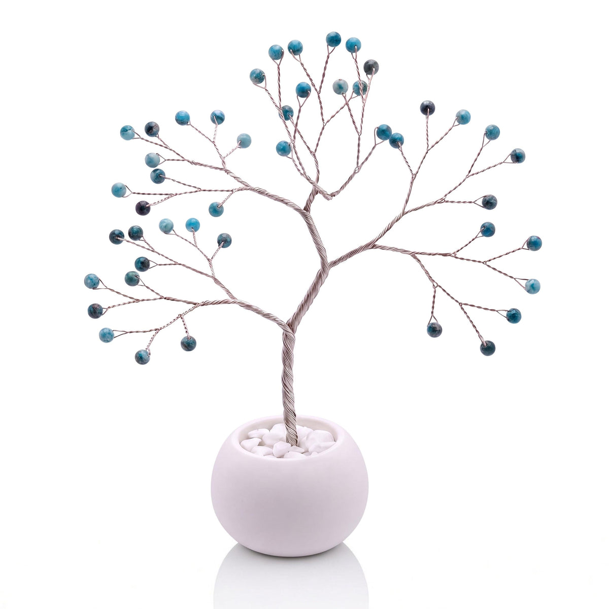 Silver-plated wire tree with polished teal blue apatite beads in a white bowl with white pebbles