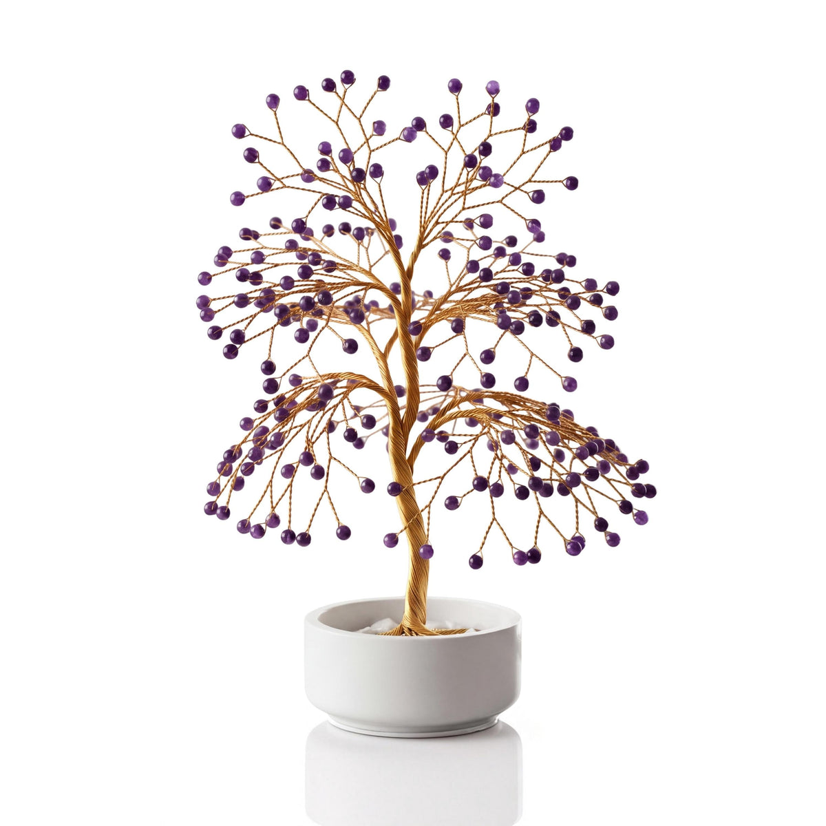 Gold-plated wire tree with polished deep purple amethyst spheres in a white ceramic bowl