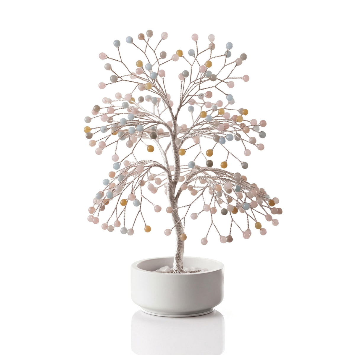 Silver-plated wire tree with polished pastel morganite, heliodor and aquamarine spheres in a white ceramic bowl