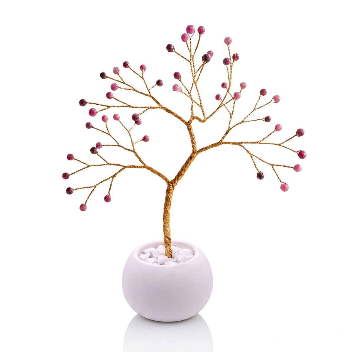 Gold-plated wire tree with faceted ruby beads in a white bowl with white pebbles