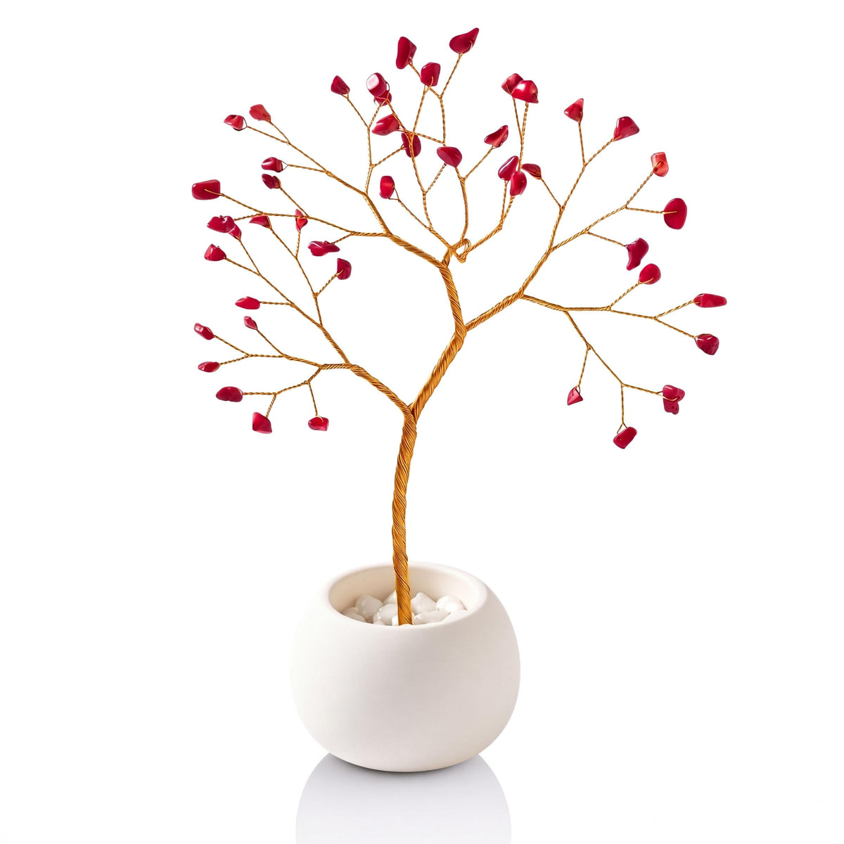 Gold-plated wire tree with red coral chips in a white ceramic bowl filled with white pebbles