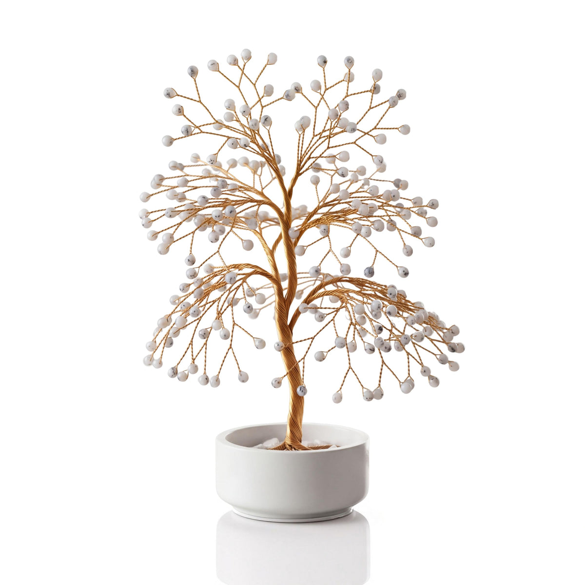 Gold-plated wire tree with polished milky white dendritic opal spheres in a white ceramic bowl