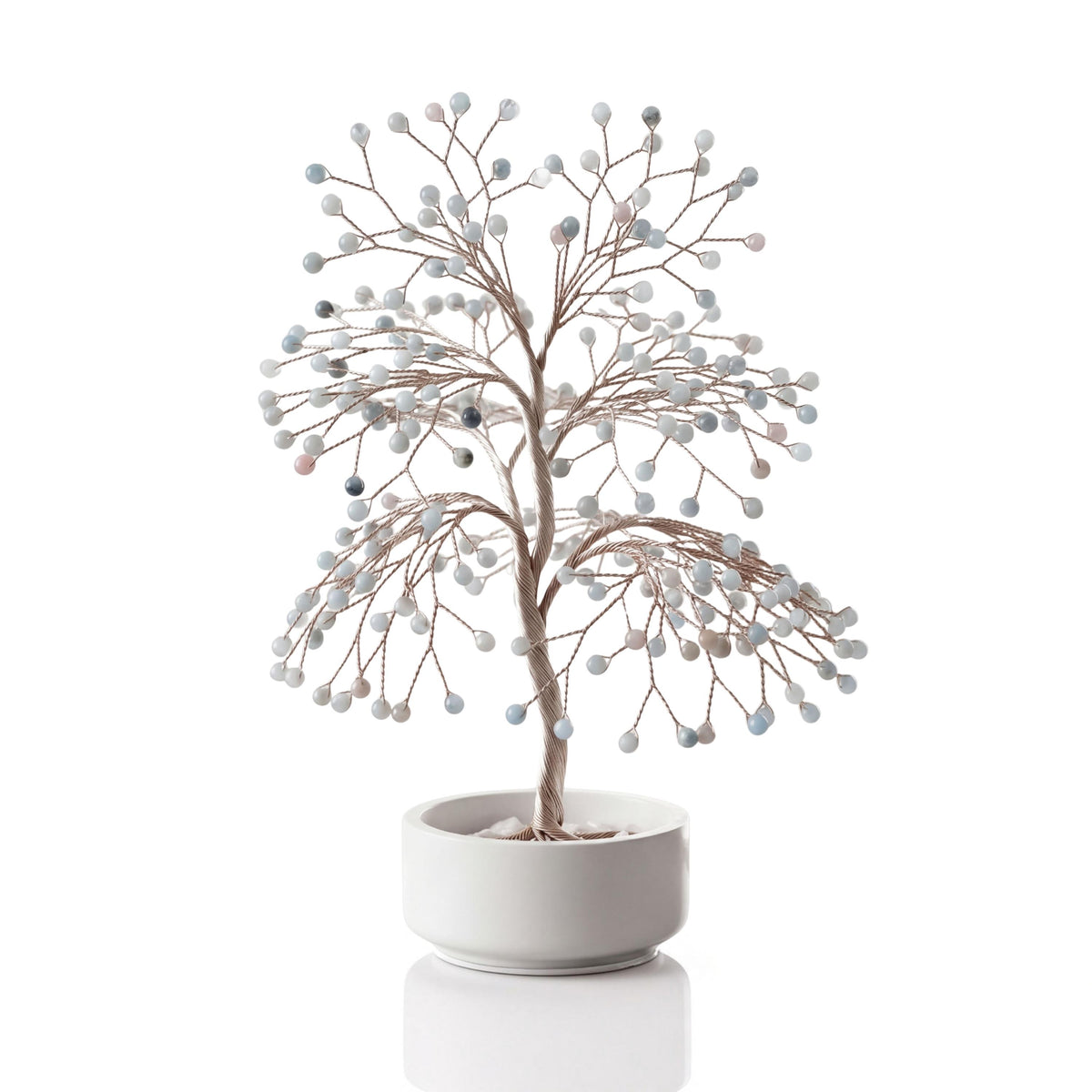 Silver-plated wire tree with polished pale sea glass blue aquamarine spheres in a white ceramic bowl