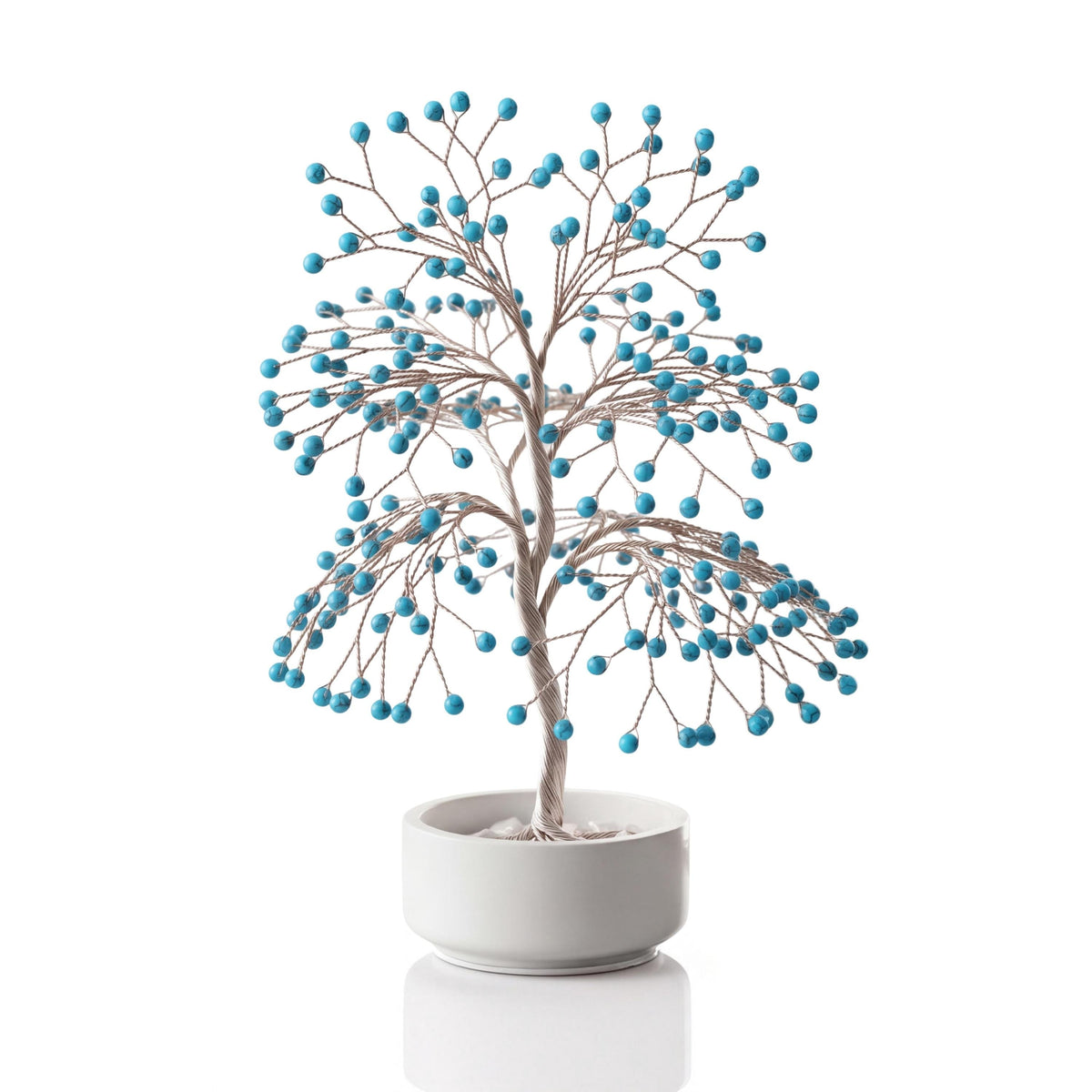 Silver-plated wire tree with polished turquoise blue howlite spheres in a white ceramic bowl