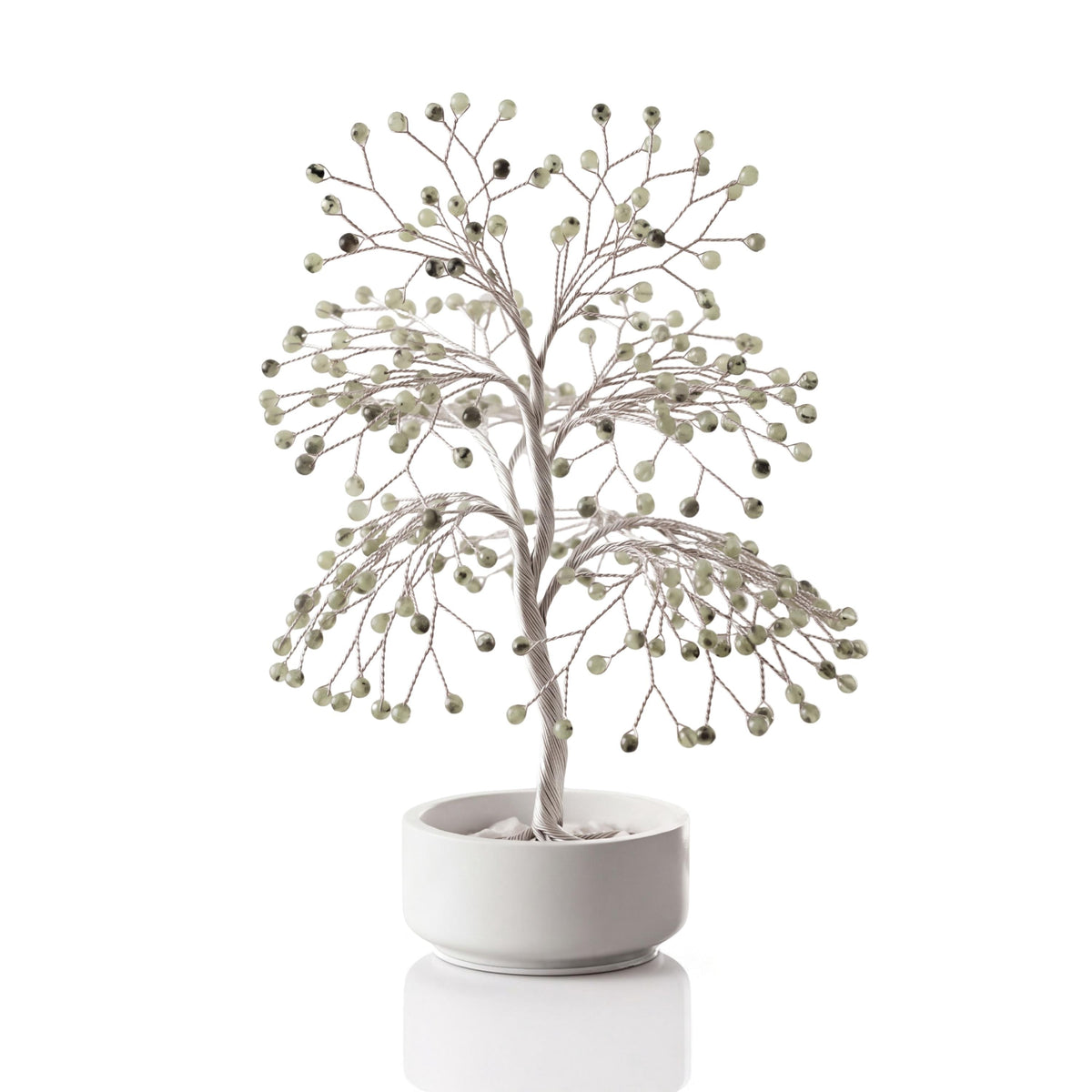 Silver-plated wire tree with polished light green prehnite beads in a white ceramic bowl