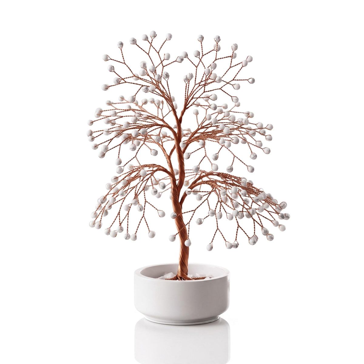 Copper wire tree with polished white howlite beads with grey marbling in a plain white ceramic bowl