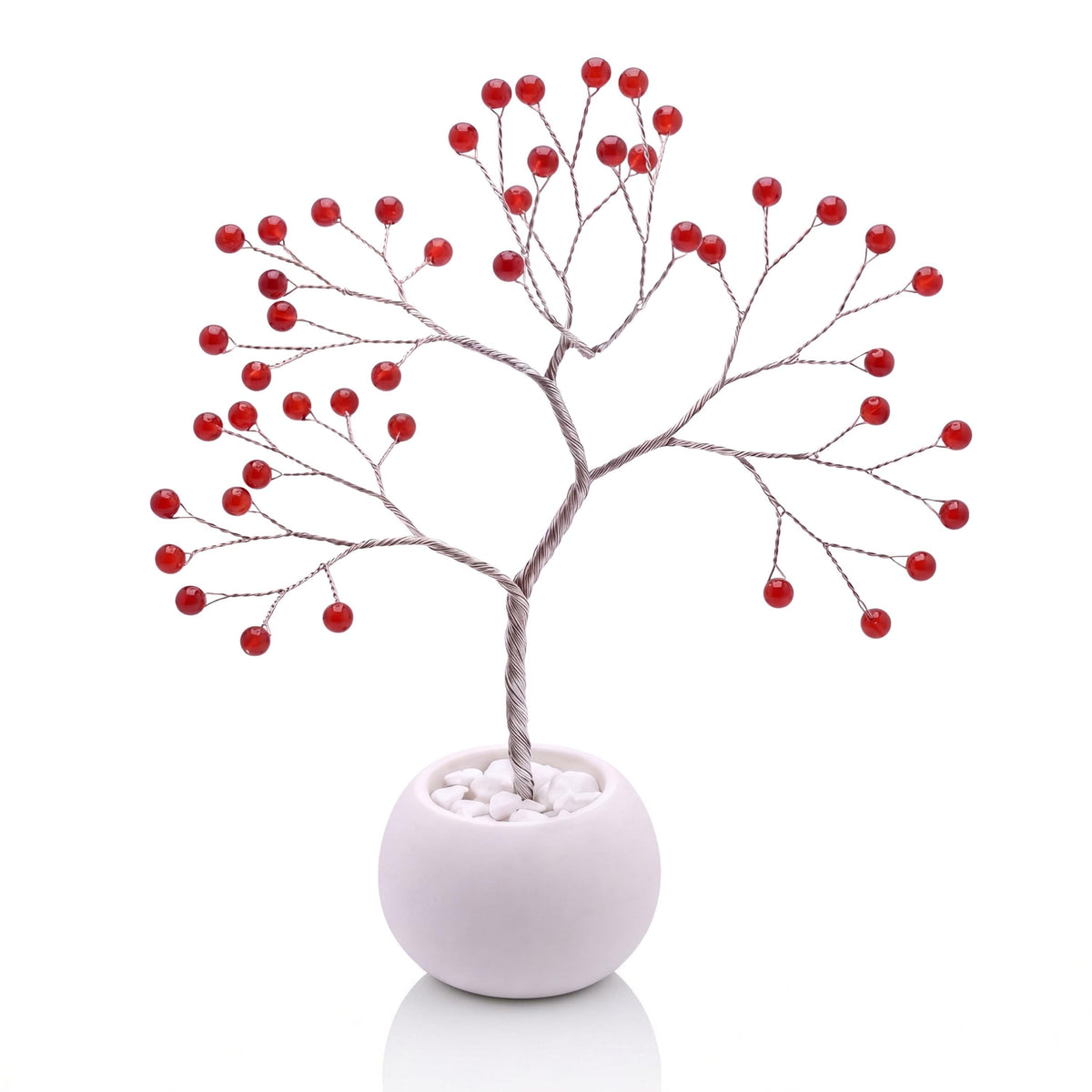 Silver-plated wire tree with polished cherry red carnelian beads in a white bowl with white pebbles