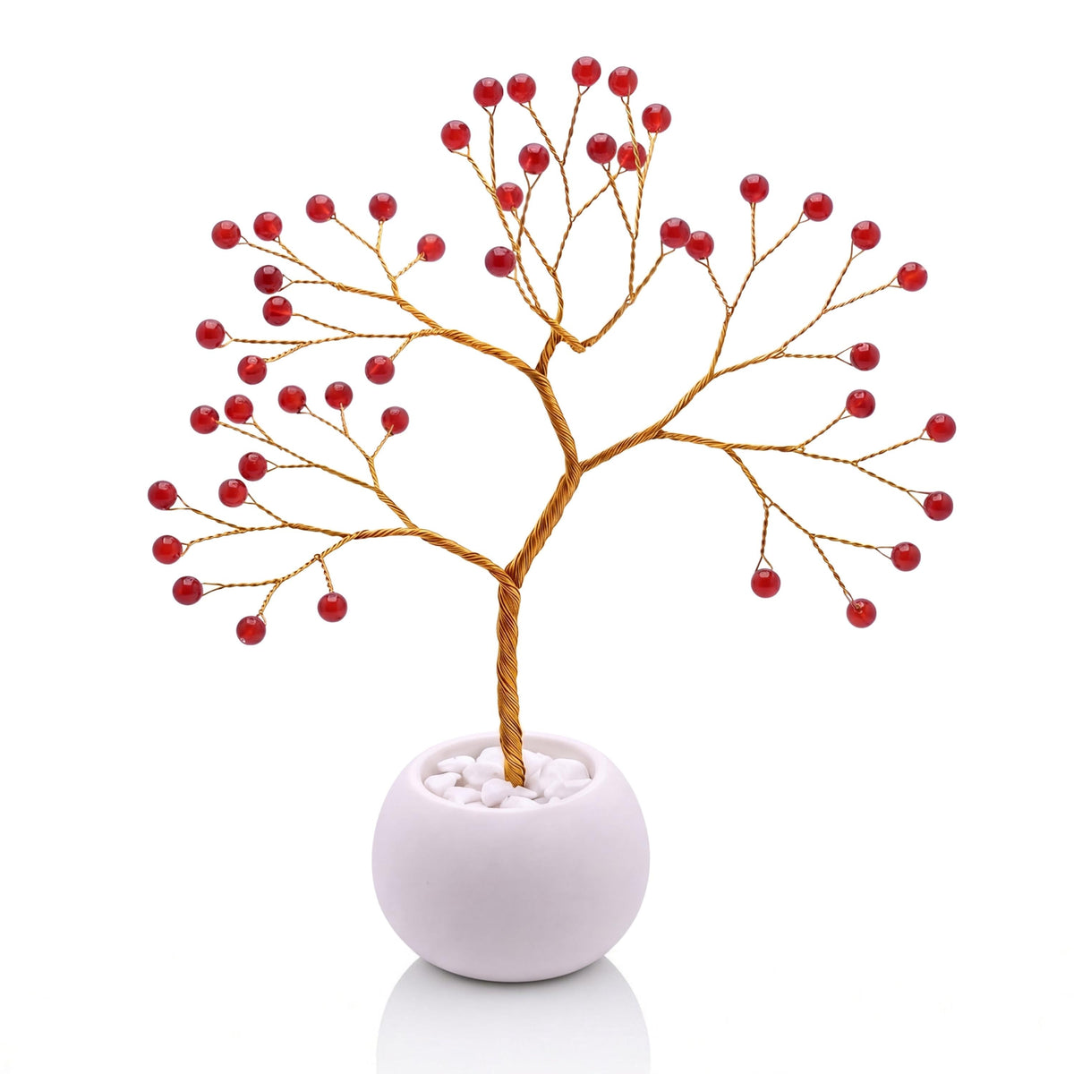 Gold-plated wire tree with polished cherry red carnelian beads in a white bowl with white pebbles