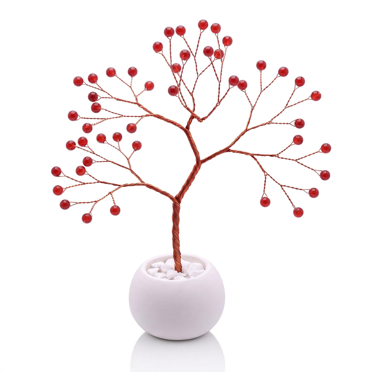 Copper wire tree with polished cherry red carnelian beads in a plain white bowl filled with white pebbles