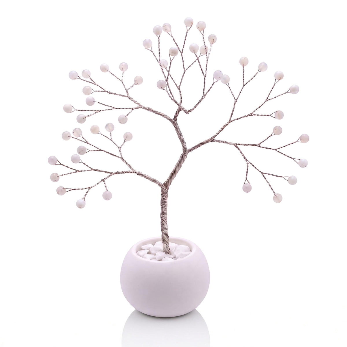 Silver-plated wire tree with polished snowy white dendritic opal beads with black dots in a white bowl with white pebbles