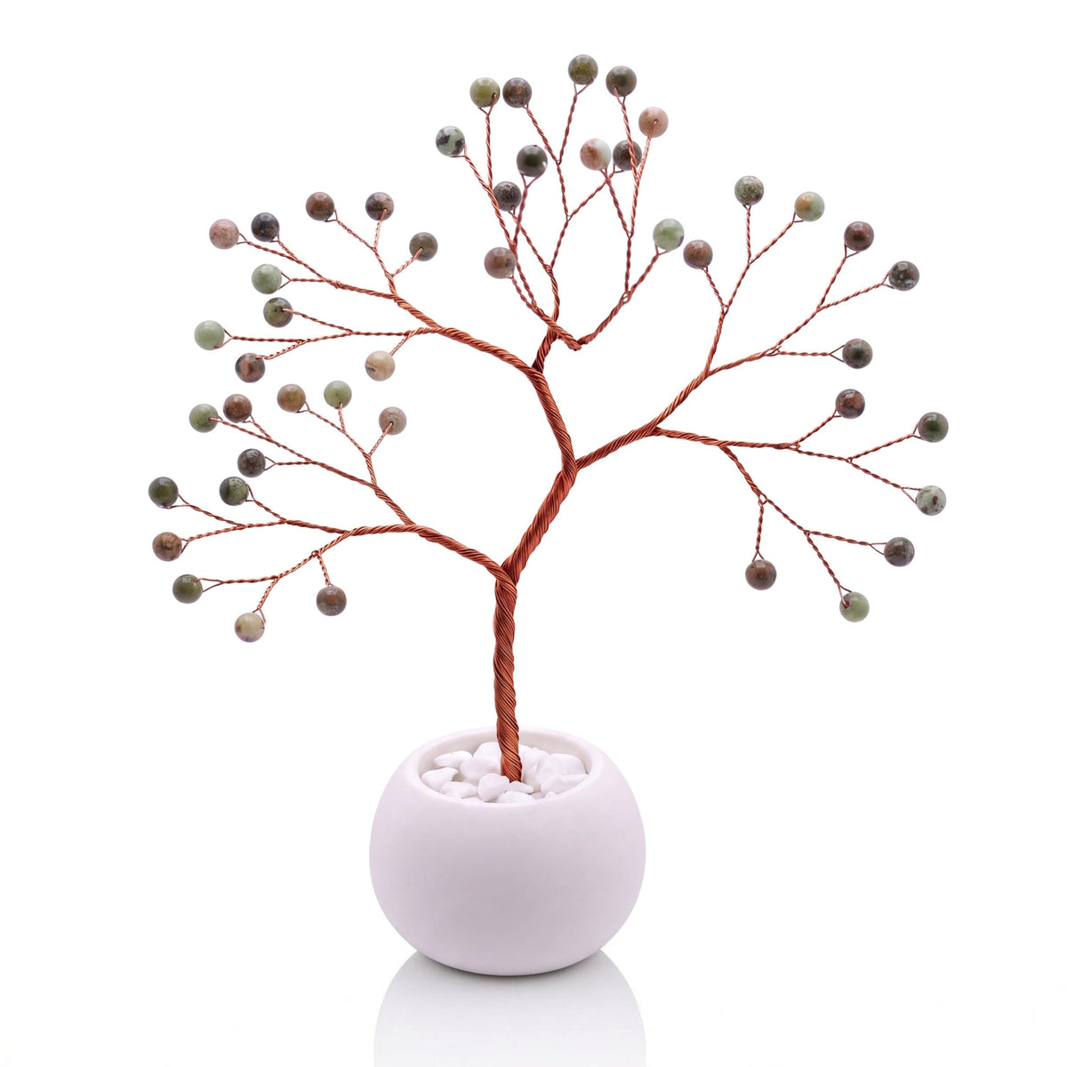 Copper wire tree with polished pistachio green opal beads in a plain white bowl filled with white pebbles