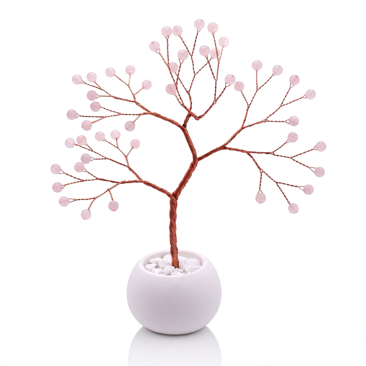 Copper wire tree with polished soft pink rose quartz beads in a plain white bowl filled with white pebbles
