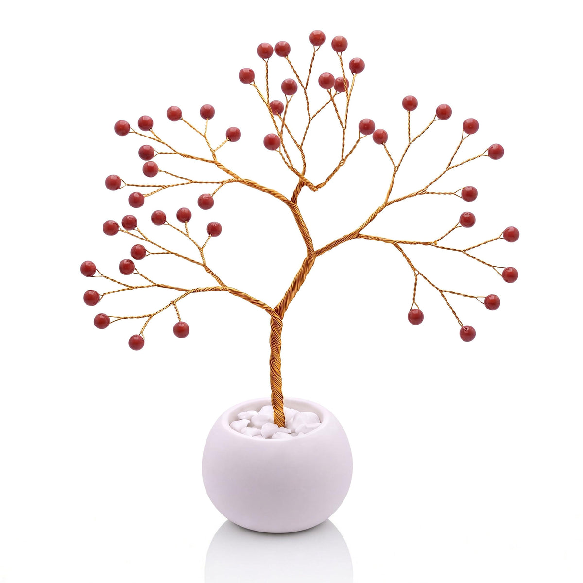 Gold-plated wire tree with polished brick red jasper beads in a white bowl with white pebbles