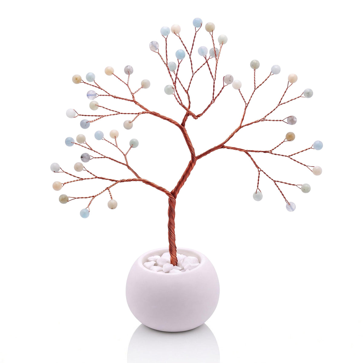 Copper wire tree with polished milky sea blue aquamarine beads in a plain white bowl filled with white pebbles