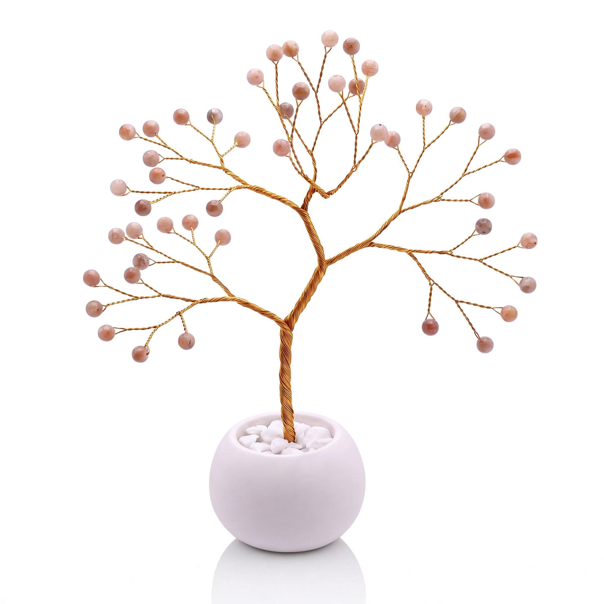Gold-plated wire tree with polished tangerine orange moonstone beads in a white bowl with white pebbles
