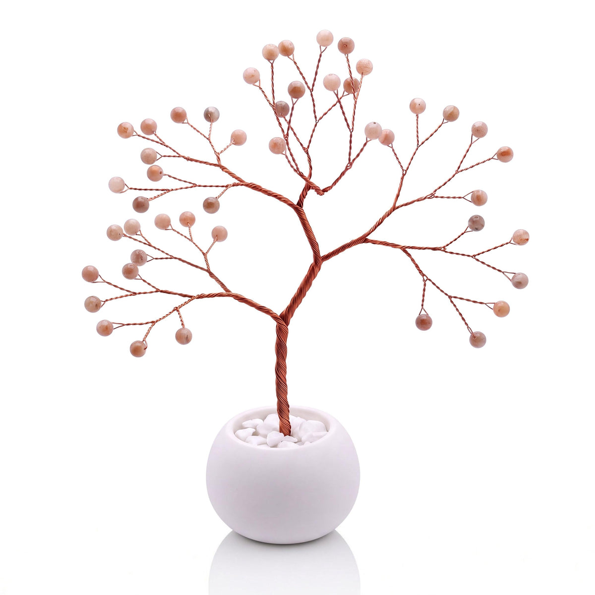 Copper wire tree with polished tangerine orange moonstone beads in a plain white bowl filled with white pebbles