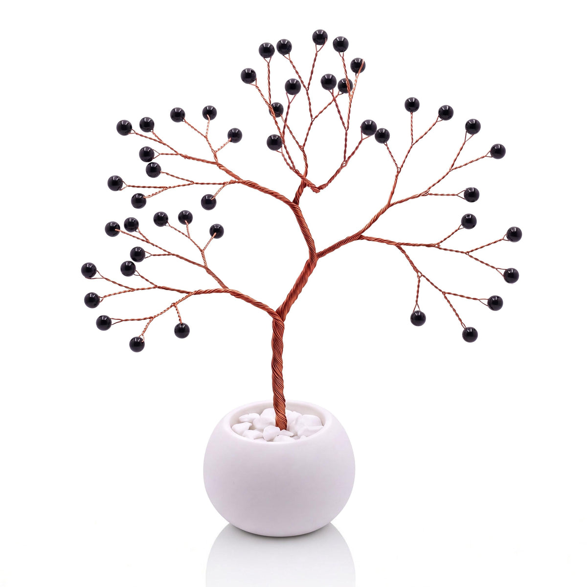 Copper wire tree with polished glossy black obsidian beads in a plain white bowl filled with white pebbles