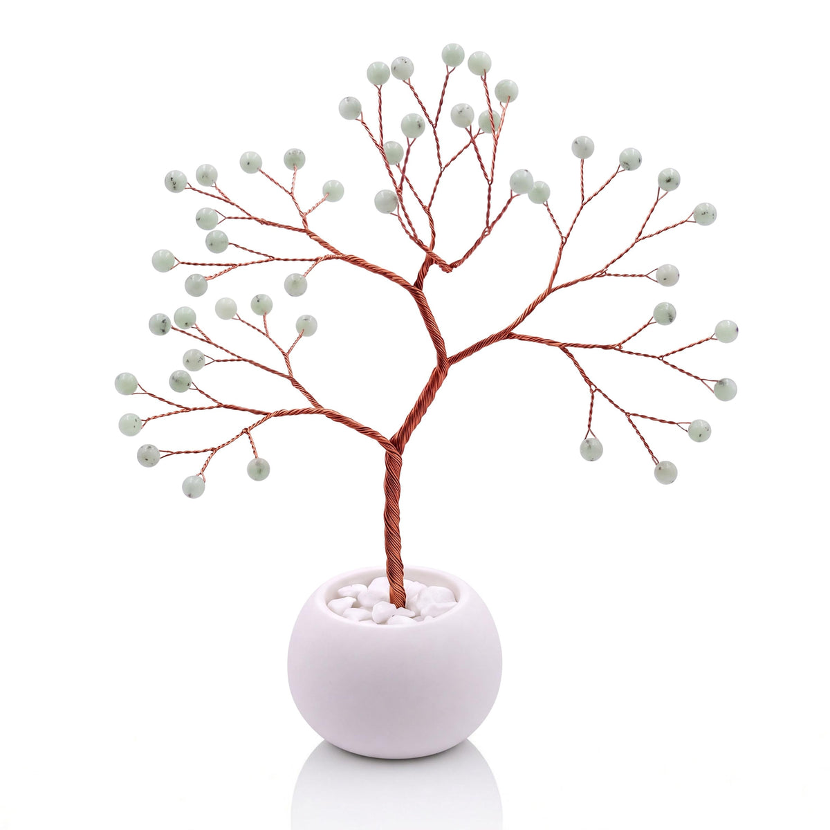 Copper wire tree with polished celadon green hemimorphite beads in a plain white bowl filled with white pebbles