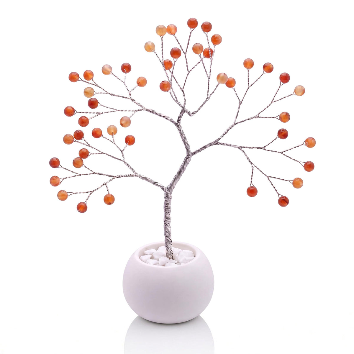 Silver-plated wire tree with polished marmalade orange carnelian beads in a white bowl with white pebbles