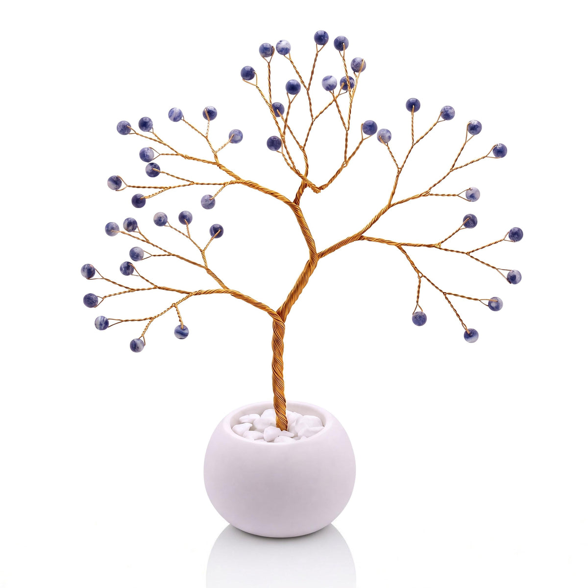 Gold-plated wire tree with polished denim blue sodalite beads with white veining in a white bowl with white pebbles