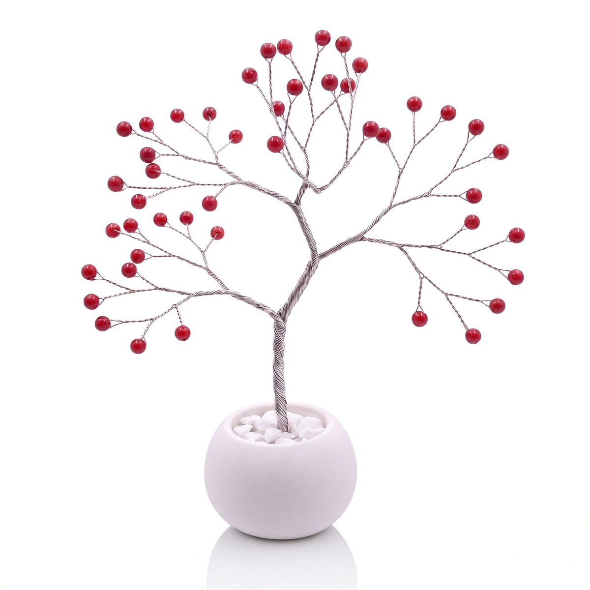 Silver-plated wire tree with polished red coral beads in a white bowl with white pebbles