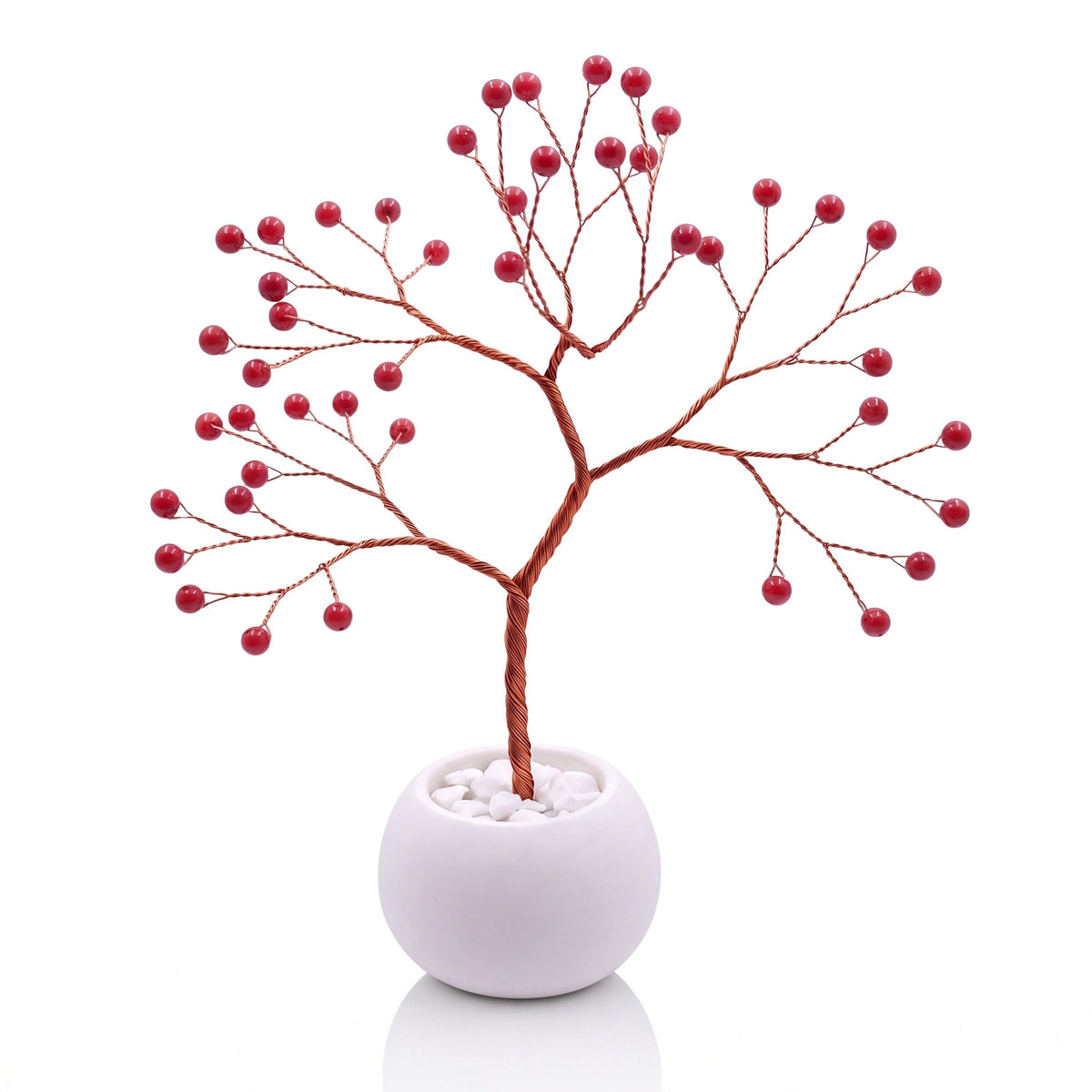 Copper wire tree with polished red coral beads in a plain white bowl filled with white pebbles