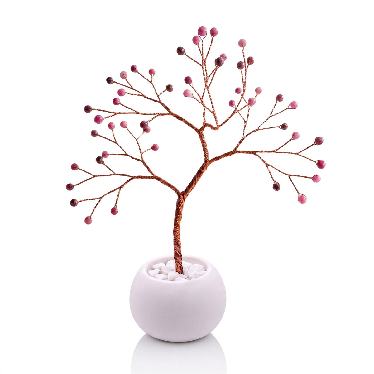 Copper wire tree with faceted ruby beads in a plain white bowl filled with white pebbles
