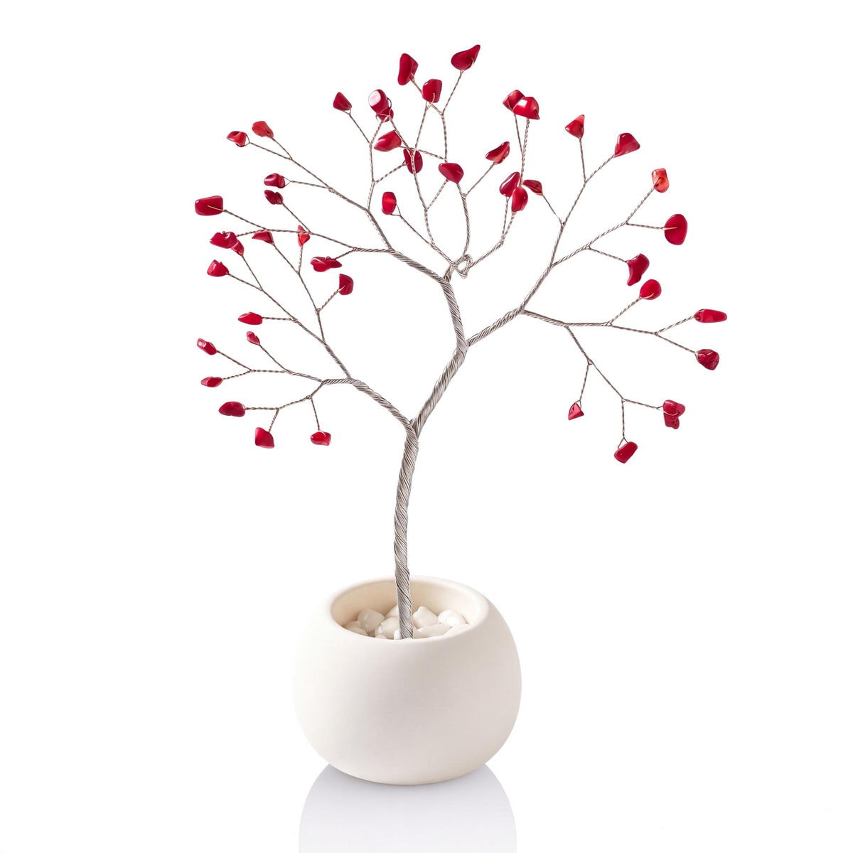 Silver-plated wire tree with red coral chips in a white ceramic bowl filled with white pebbles