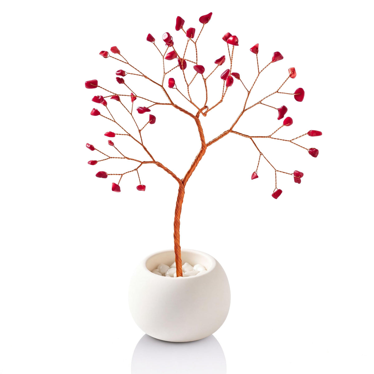 Copper wire tree with red coral chips in a plain white bowl filled with white pebbles