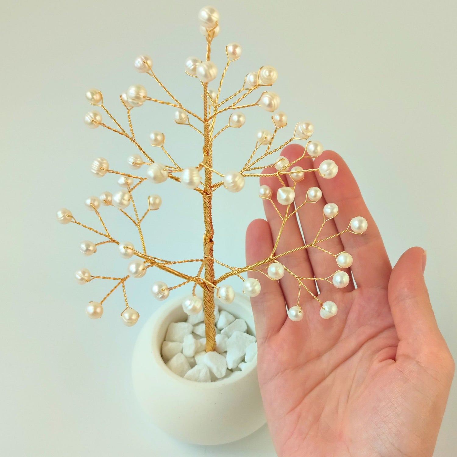 Close-up of Pearl Christmas Golden Tree branch held in hand showing natural freshwater pearls