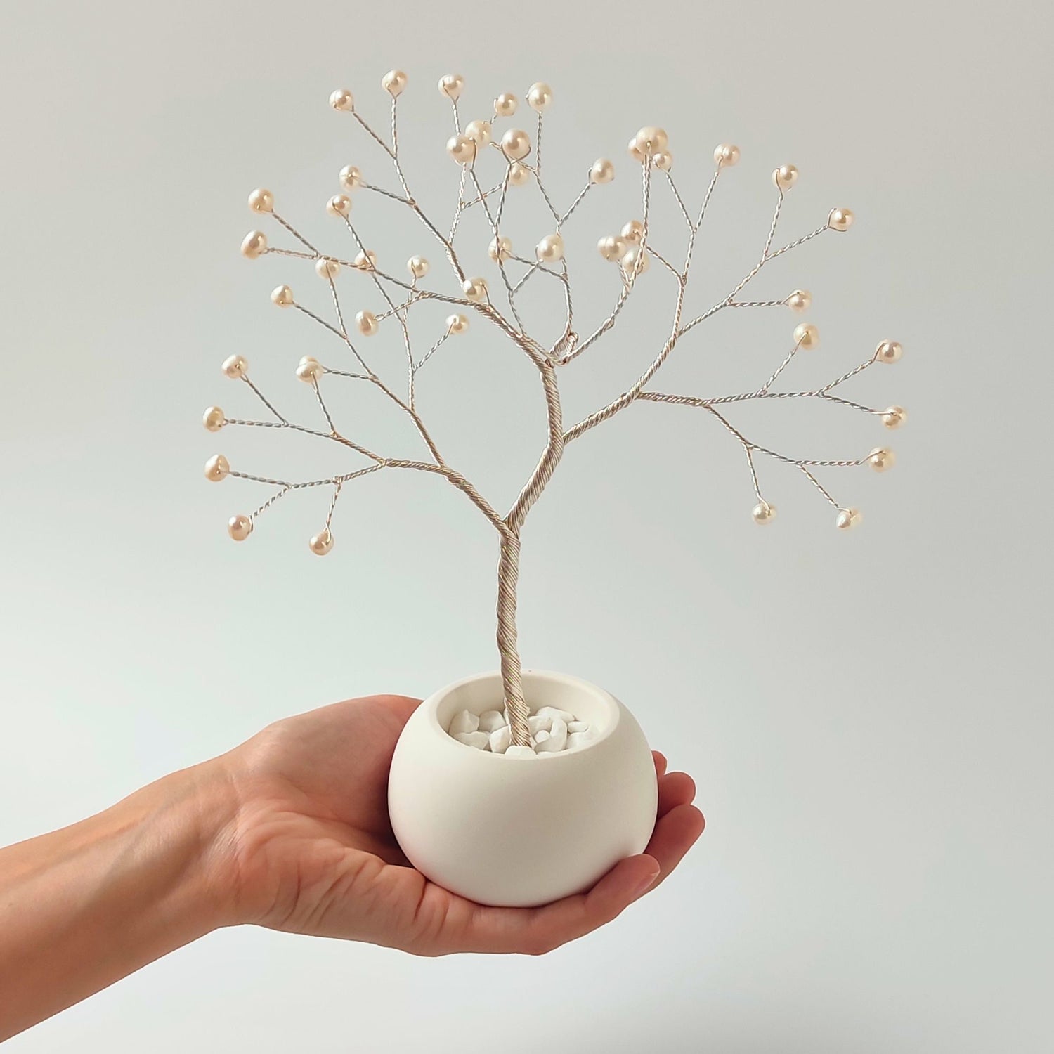 Size reference – pearl small silver tree sculpture held in hand to show scale