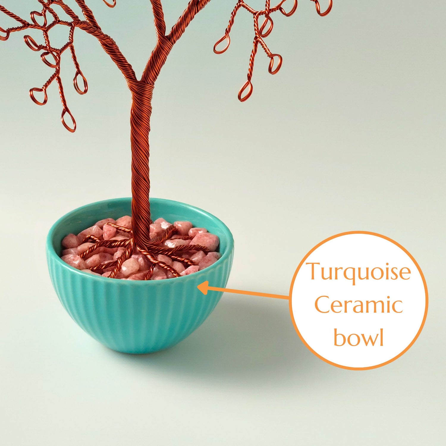 Decorative pink stone base supporting copper jewelry tree