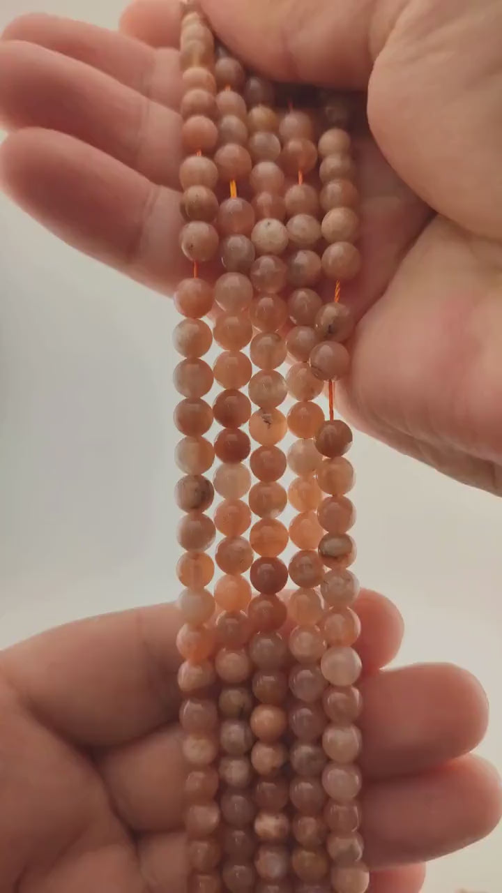 Video of strands of tangerine orange moonstone beads used for this tree, held in the hand