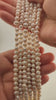 Strands of natural white freshwater pearls held in two hands, the pearls used for the tree