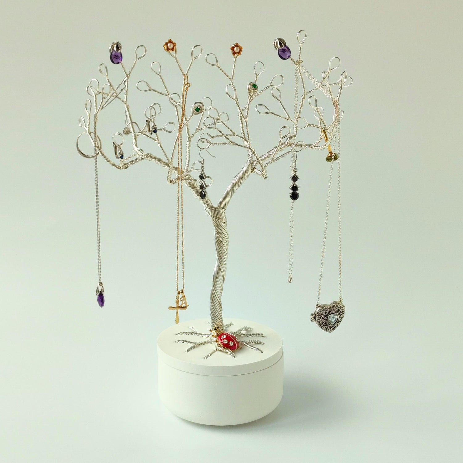 Silver jewelry tree stand displaying rings, earrings and necklaces