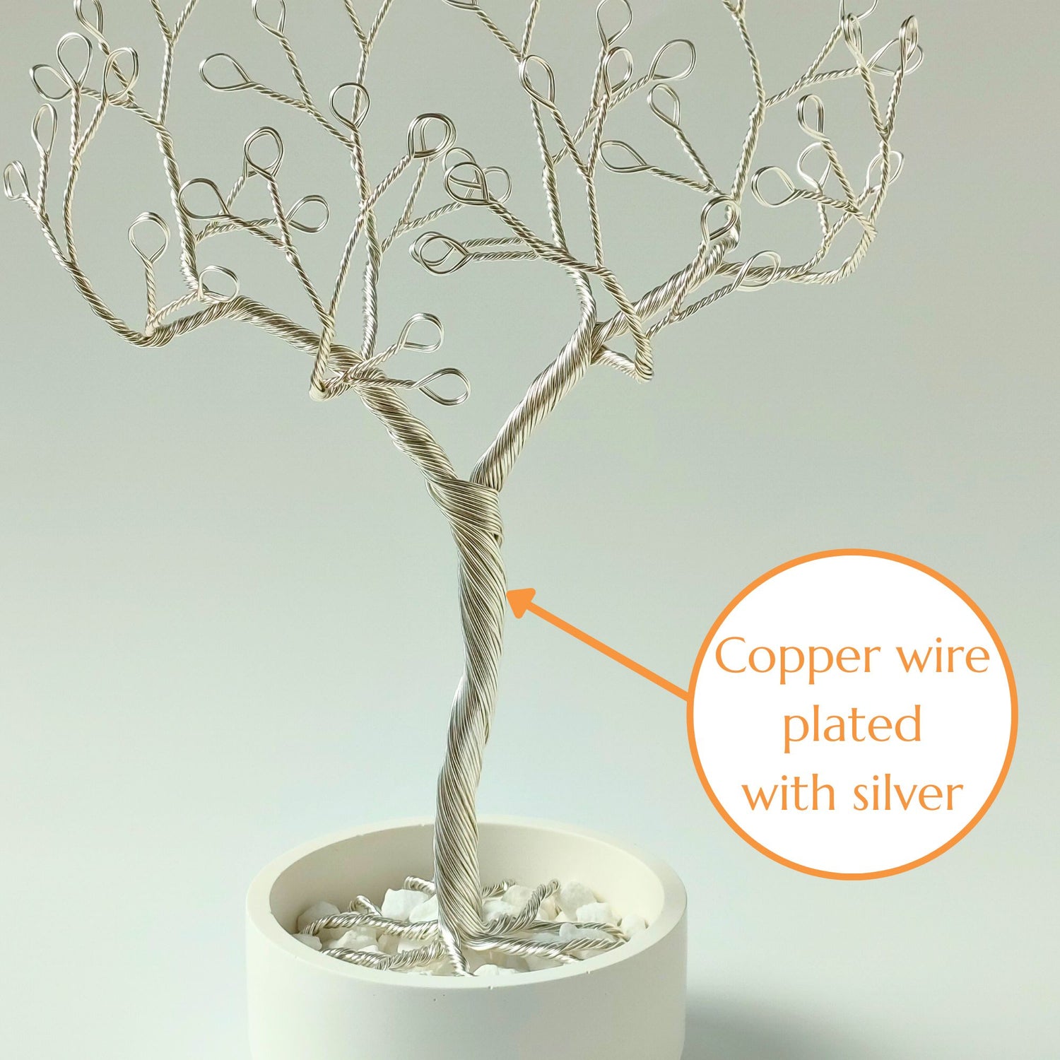 Close-up of silver plated wire jewelry stand trunk with material annotation and decorative stones